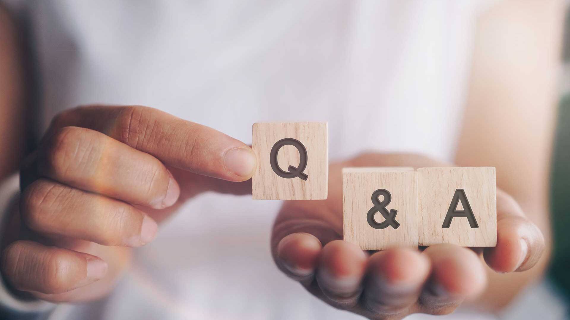 Person hält Holzwürfel mit den Buchstaben Q und A für die Fragestunde in der Hand
