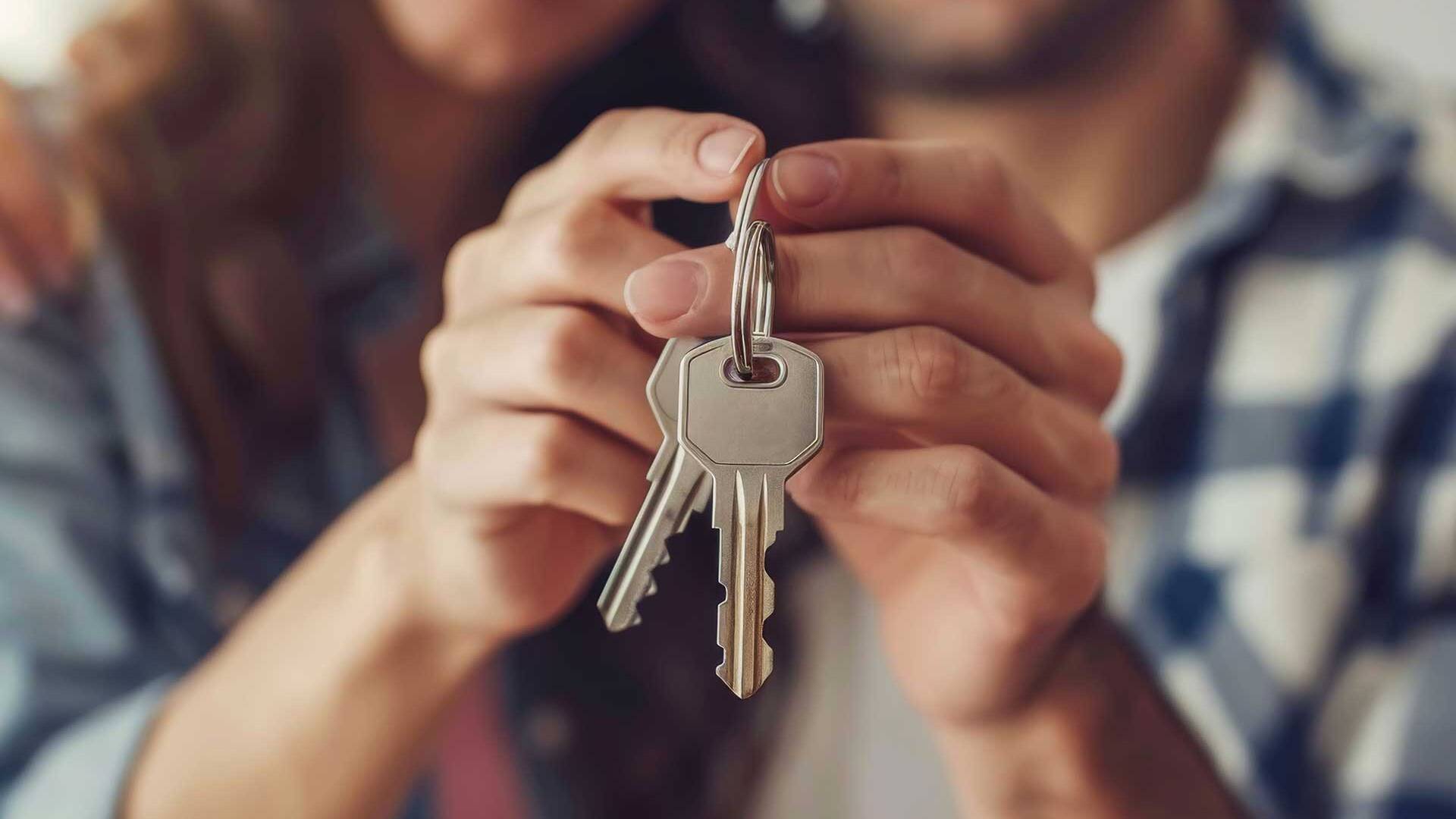 Junges Paar hält nach dem Immobilienkauf die Schlüssel in den Händen